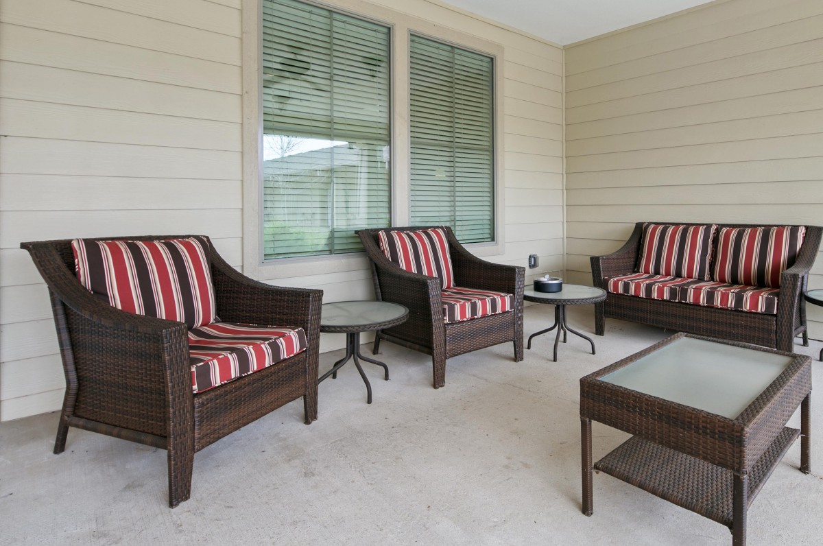 A cozy patio setup featuring wicker chairs with striped cushions and a glass-topped coffee table.