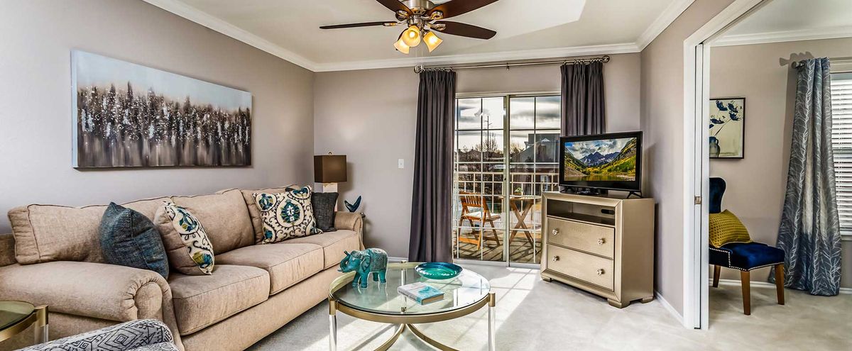 A cozy living room with a sofa, coffee table, television, and access to a balcony.