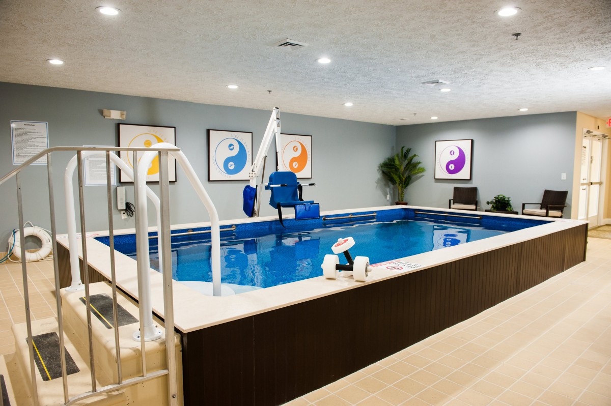 A modern indoor therapy pool equipped with accessible features and colorful decor.