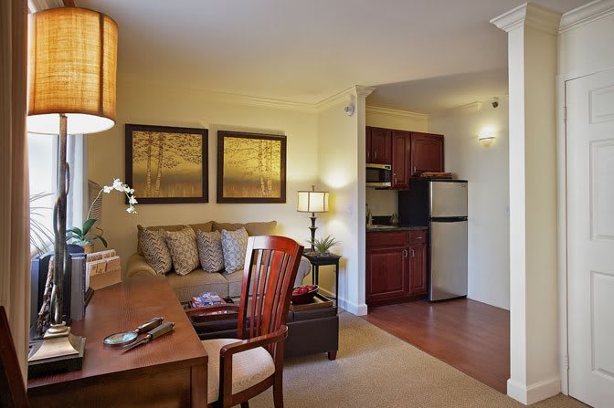A cozy living area with a sofa and kitchenette in the background, featuring warm lighting and elegant decor.