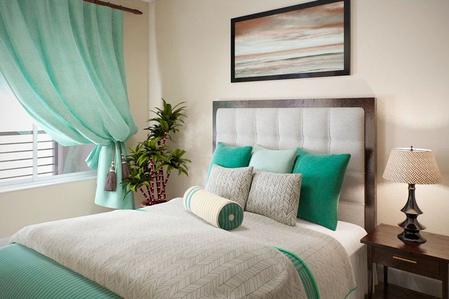 A modern bedroom with teal accents featuring a neatly made bed, decorative pillows, artwork, and a potted plant by the window.