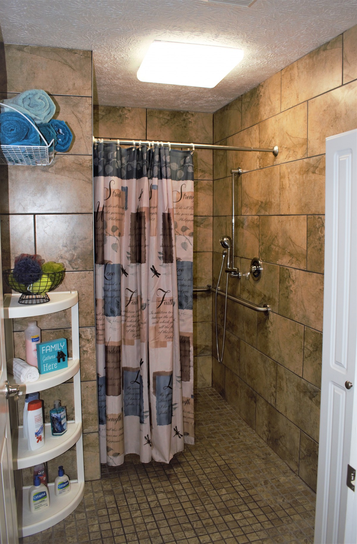 A tiled bathroom with a shower area, shower curtain, and shelf holding various toiletries.