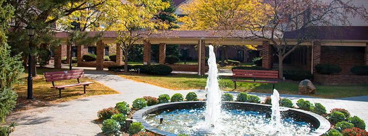 A serene garden with a flowing fountain surrounded by autumn foliage.