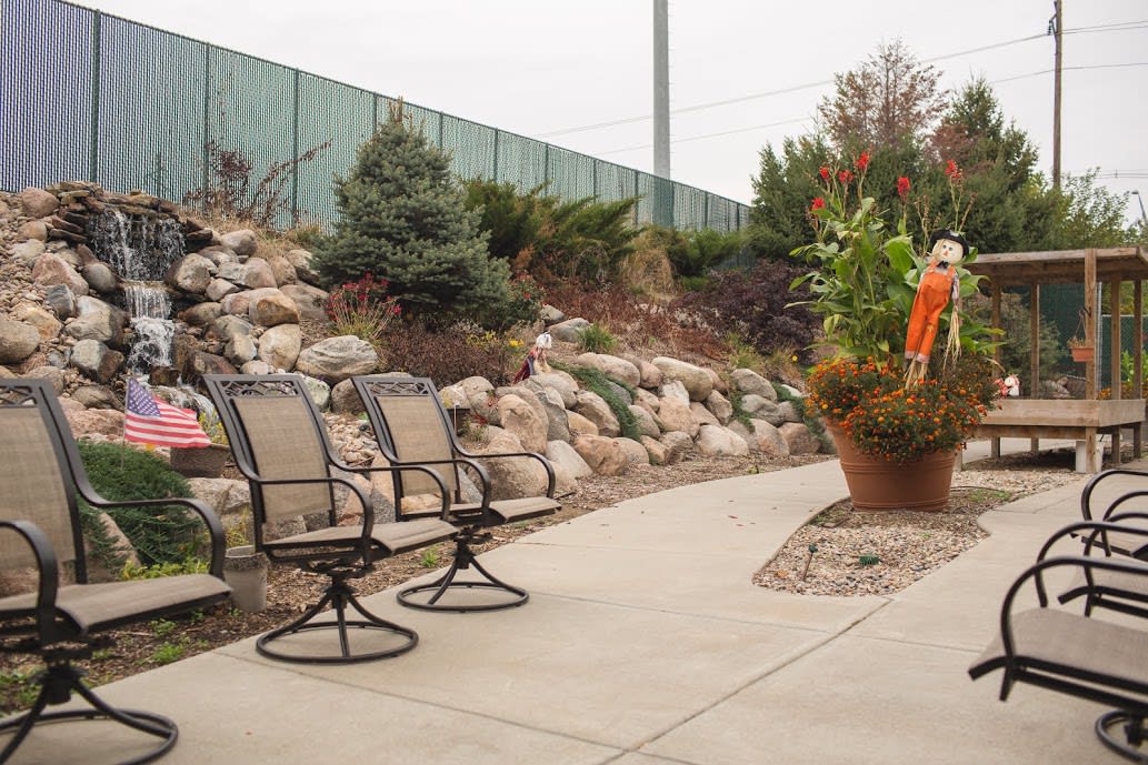 A landscaped patio area with chairs, surrounded by rocks and plants.