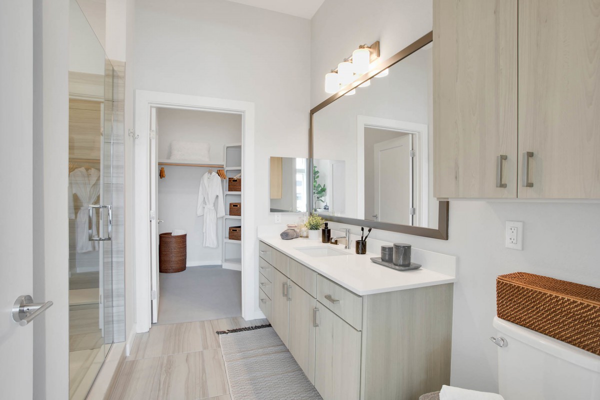 A modern, minimalist bathroom with a large mirror and sleek vanity.