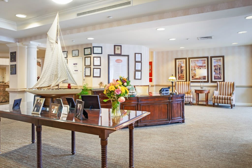 A well-decorated reception area featuring a model sailboat and a bouquet of flowers on the desk.