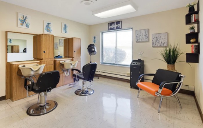 A well-lit hair salon with chairs and mirrors, featuring a tidy and welcoming interior setup.