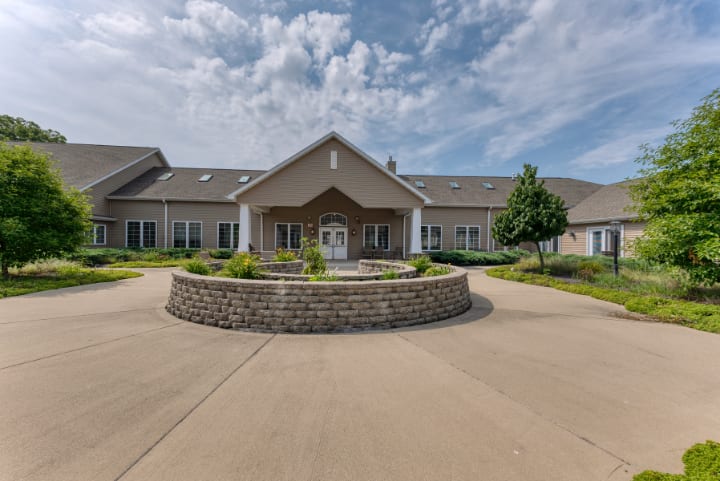 A large building with a circular driveway and landscaped area under a partly cloudy sky.