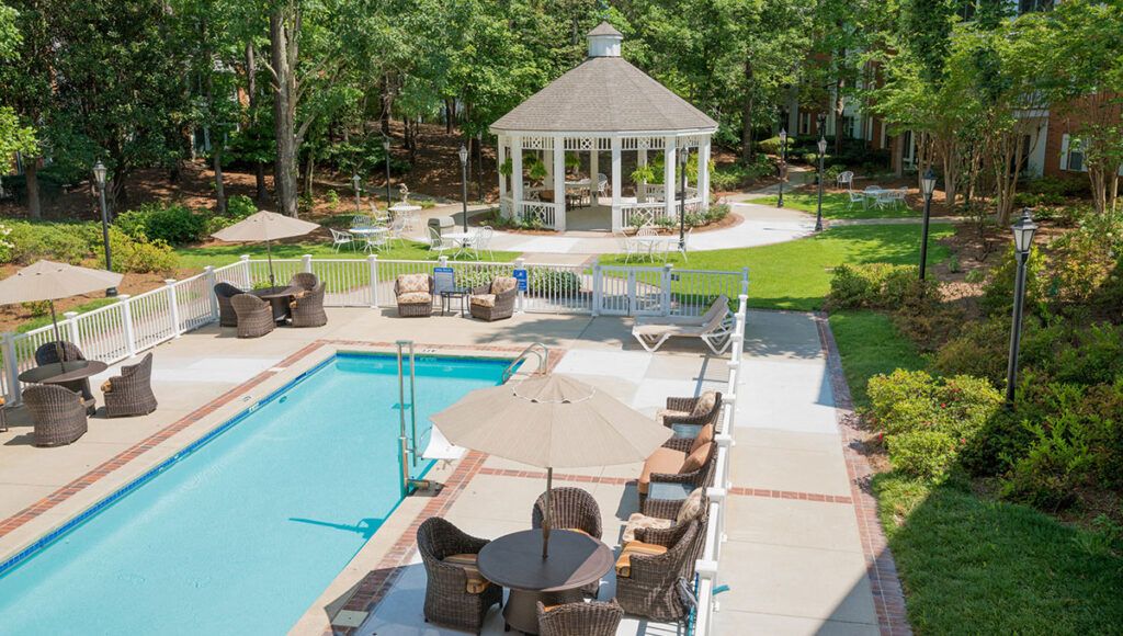 A serene outdoor setting featuring a pool with lounge chairs and a gazebo in the background.