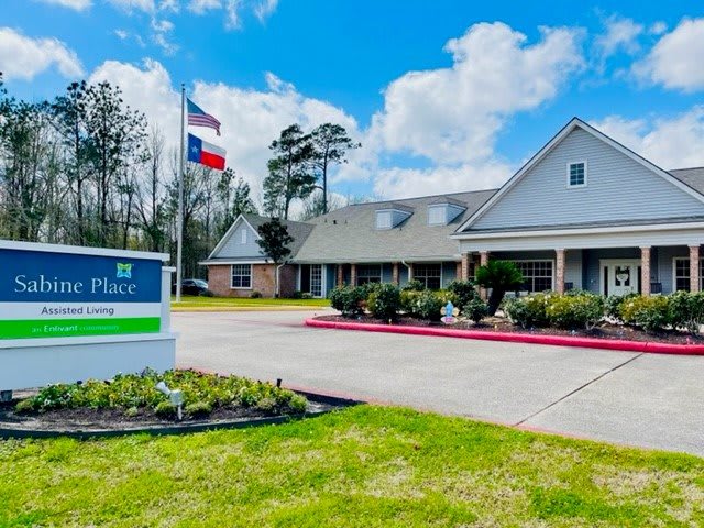 A nursing home with a well-maintained entrance and flags flying, set against a partly cloudy sky.