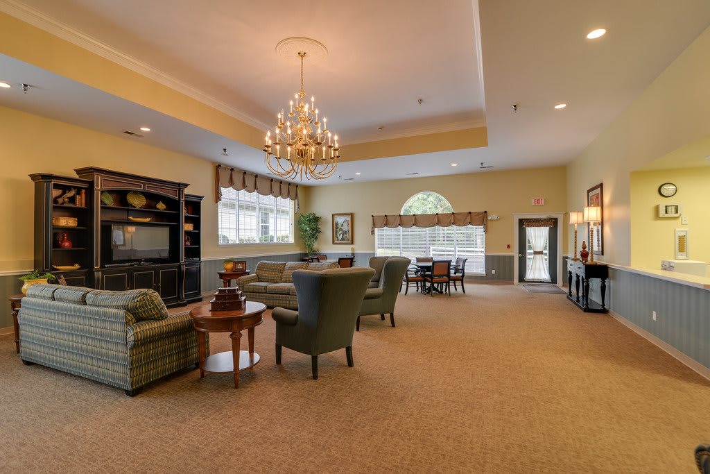 A spacious and elegant living room featuring a chandelier, comfortable seating, and large windows.