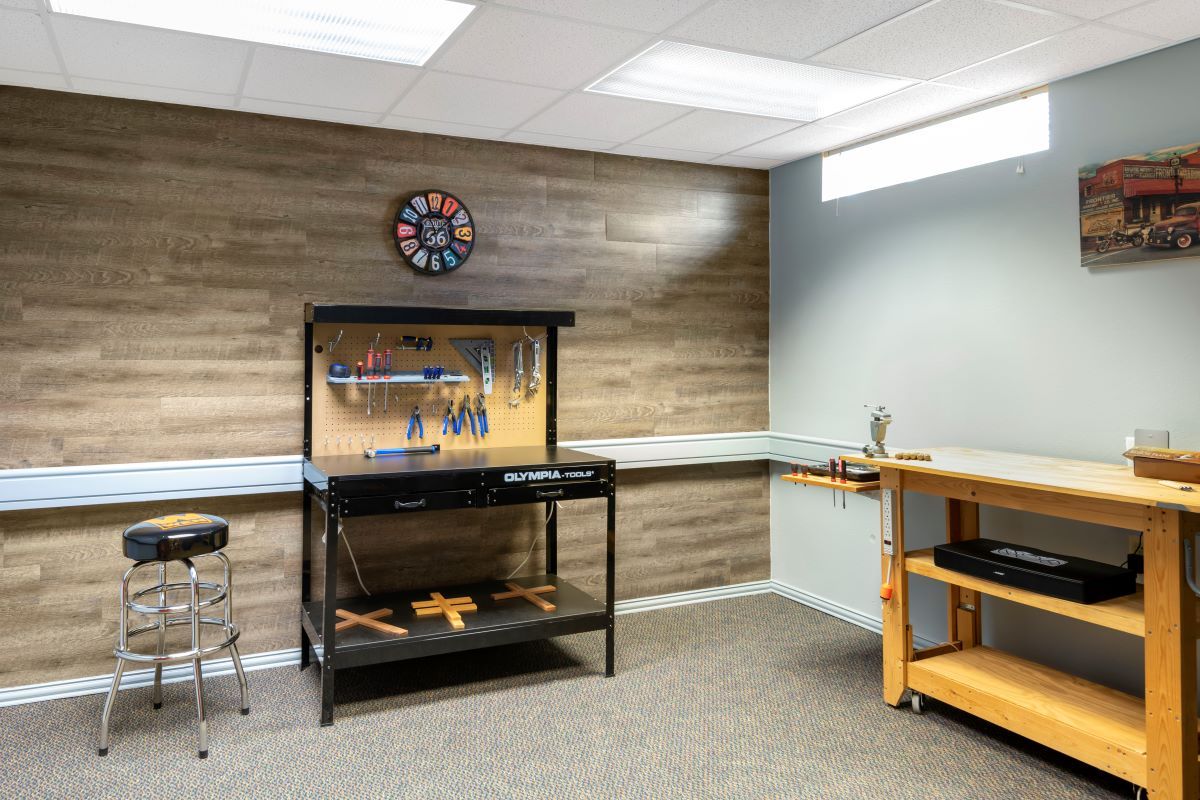 A neatly organized workshop featuring a variety of tools, a dartboard, and workbenches.