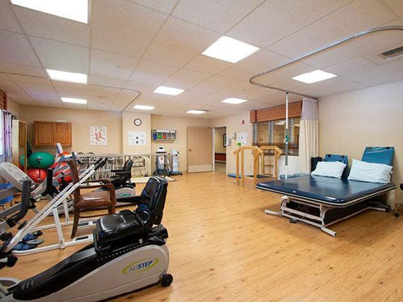 A spacious indoor gym equipped with various exercise machines and rehabilitation equipment.