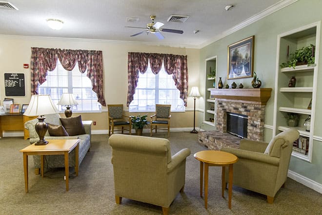 A cozy living room featuring a fireplace, comfortable seating, and large windows with elegant curtains.