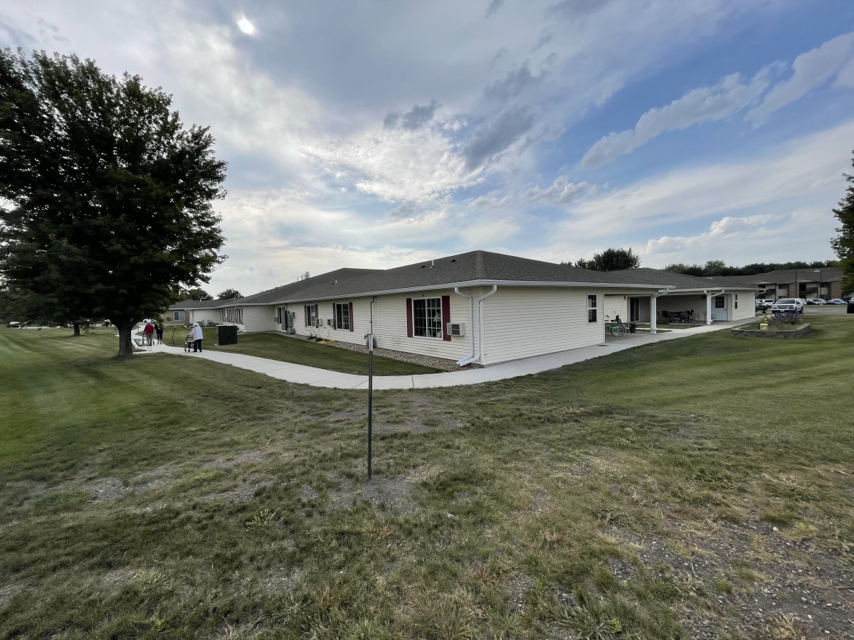 A single-story house with a lawn and sidewalk under a cloudy sky.