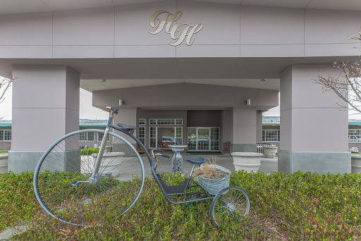 A charming entrance featuring a decorative bicycle and wheelbarrow amidst lush greenery.