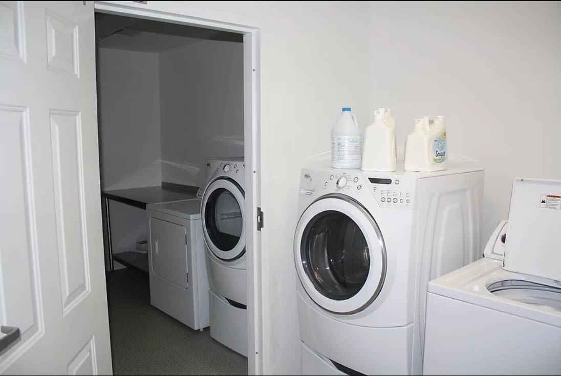 A laundry room with a washing machine and dryer, along with detergent bottles on top.