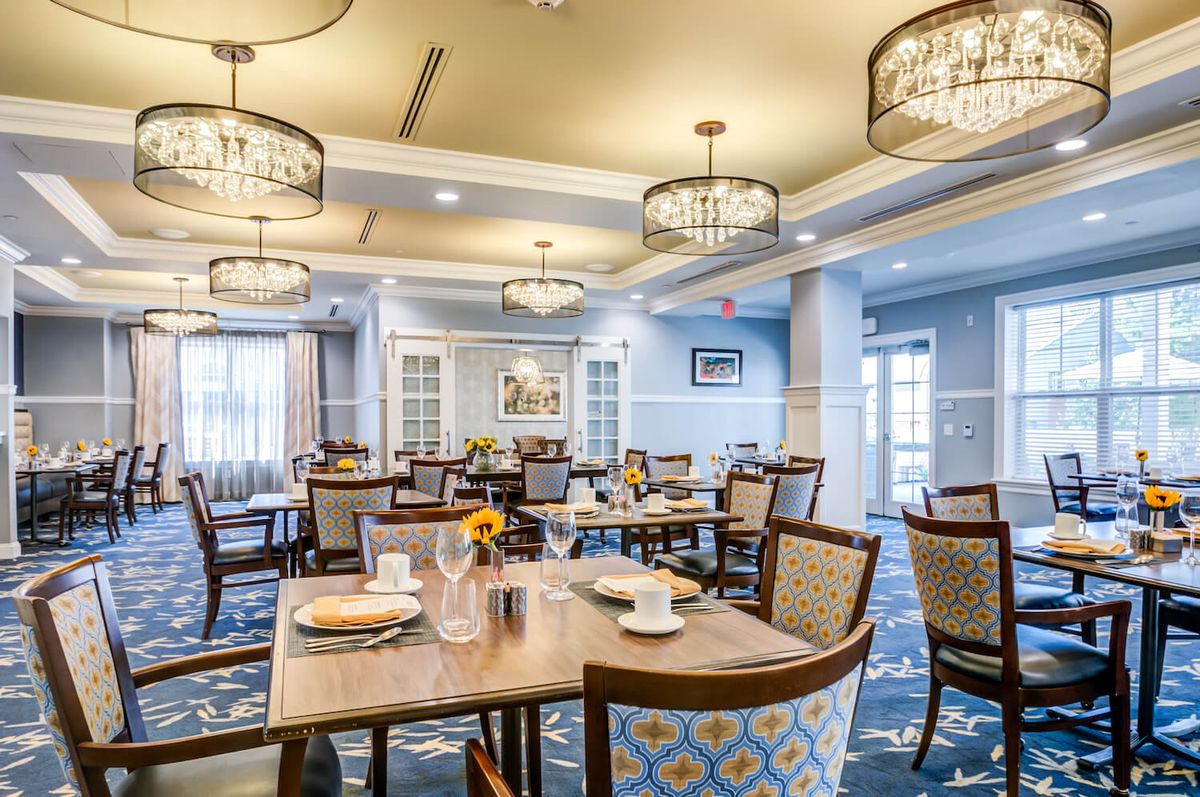An elegantly designed dining area with neatly arranged tables and chairs, featuring stylish lighting fixtures.