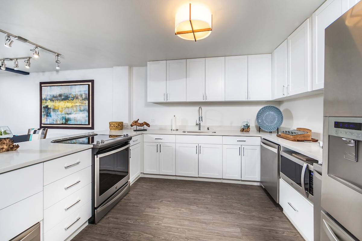 A modern kitchen with sleek white cabinets and stainless steel appliances.