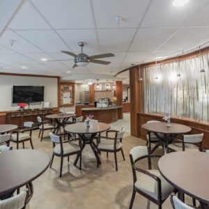 A modern dining area with tables, chairs, and a ceiling fan.
