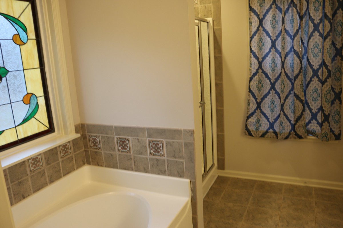 A modern bathroom featuring a bathtub and a separate shower area with tiled flooring.