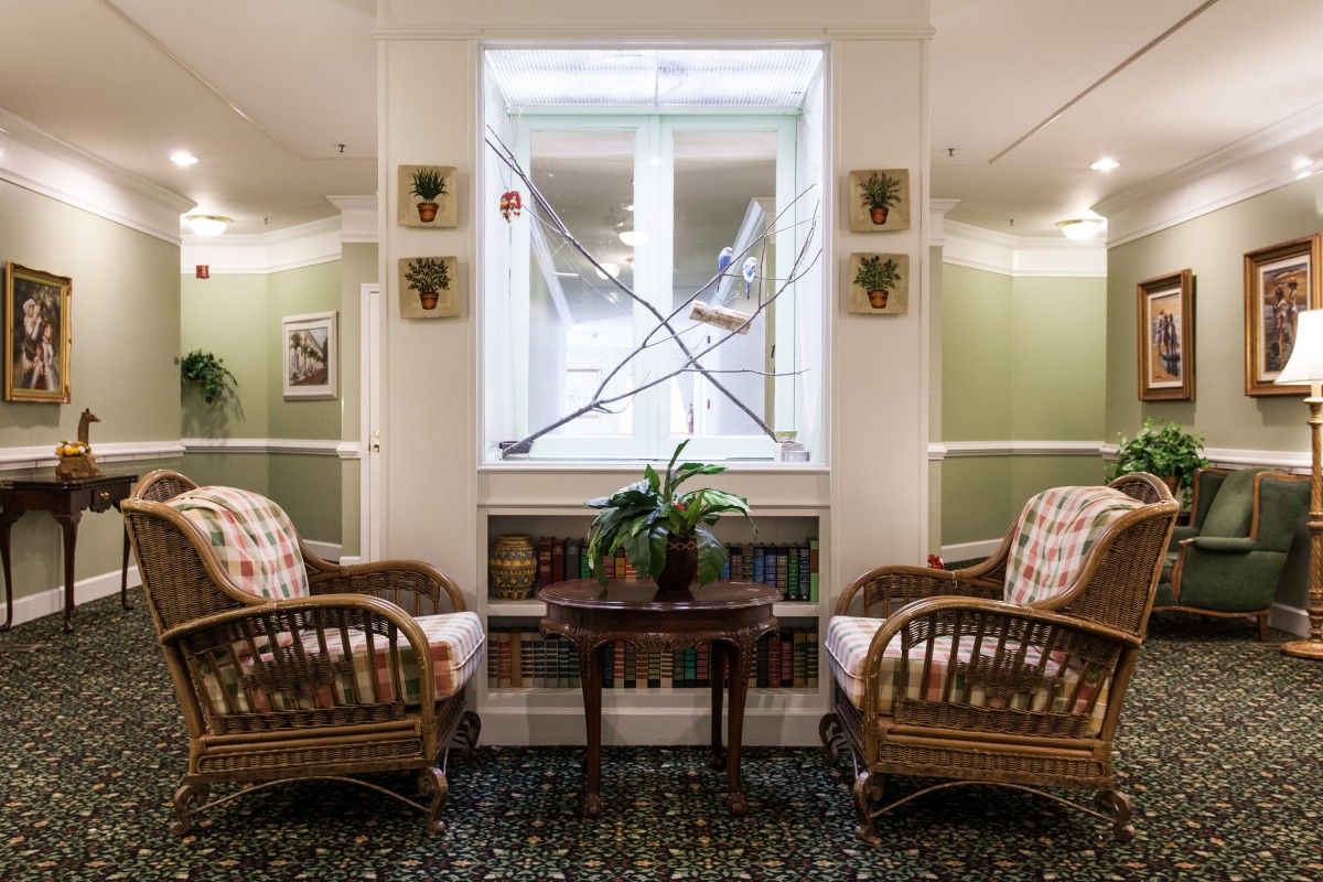 A cozy seating area with wicker chairs and decorative swords hanging above a window.