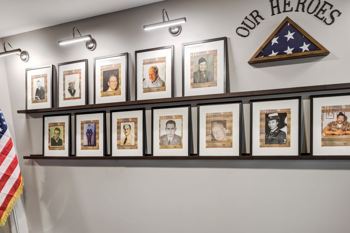 A wall display of framed photographs honoring veterans, accompanied by a folded American flag.