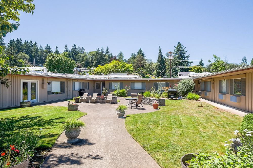 A courtyard with outdoor seating and well-maintained landscaping under a clear blue sky.