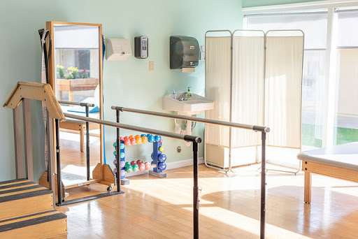 A bright and inviting physical therapy space equipped with ballet bars and fitness tools for rehabilitation.