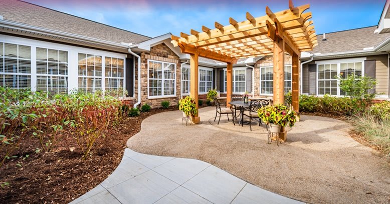 A beautifully landscaped patio with a wooden pergola and outdoor seating area.
