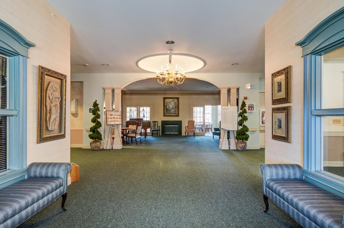 A spacious and elegantly decorated lobby area with a chandelier, furniture, and artwork.
