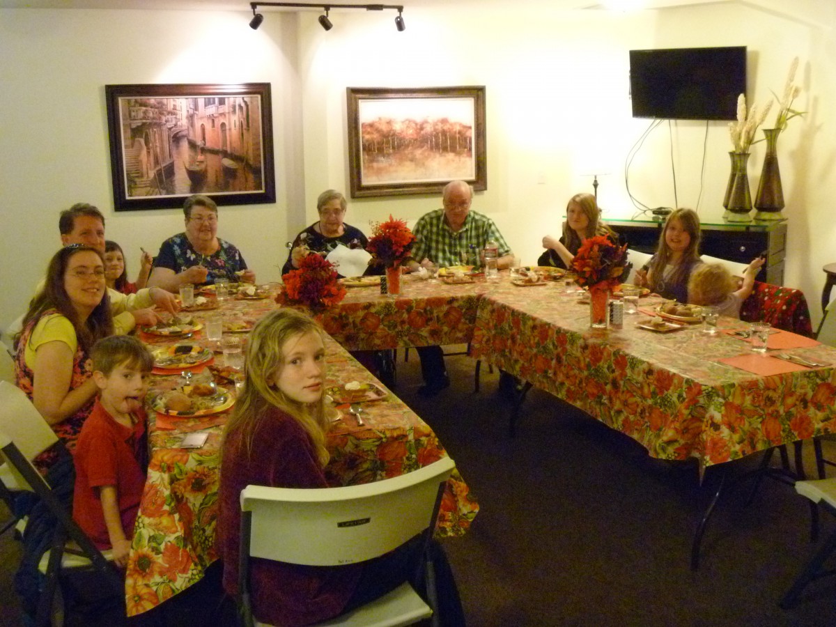 A family gathering around a dinner table, enjoying a meal together in a warmly decorated room.