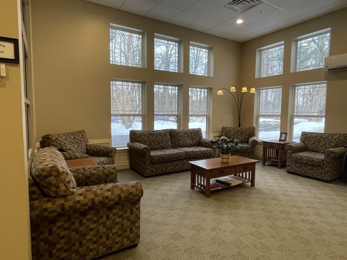 A cozy living room with multiple couches and a coffee table, surrounded by large windows.