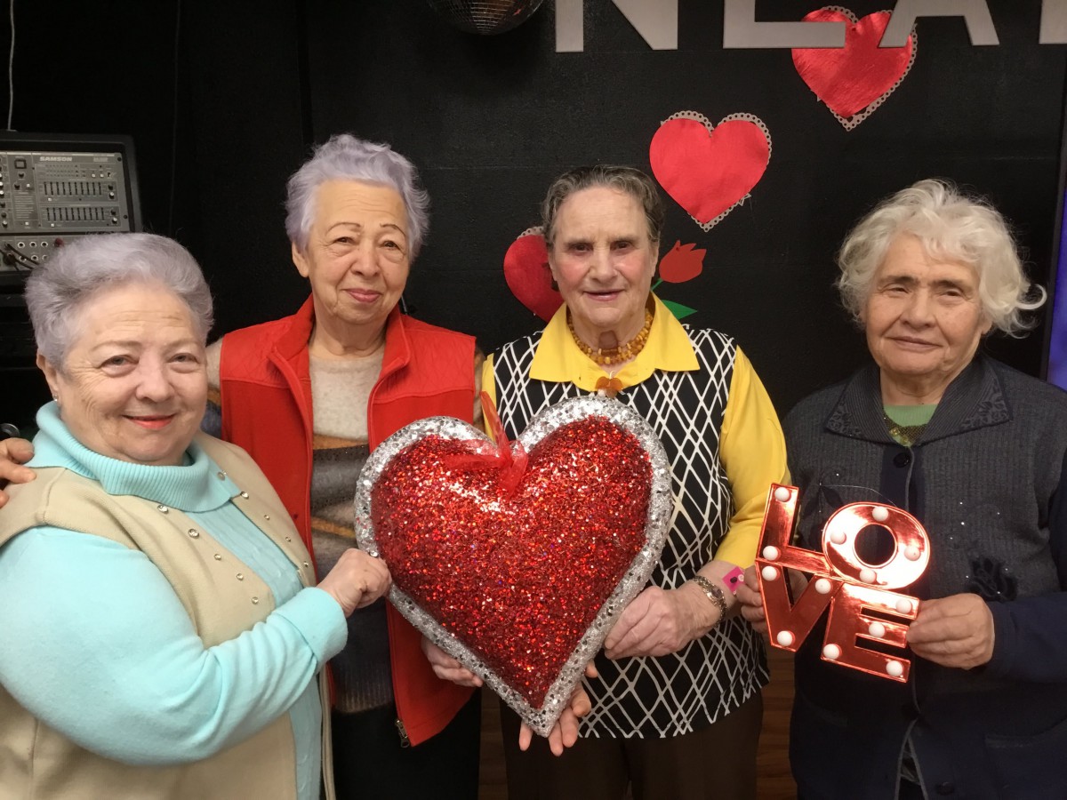 A group of seniors joyfully holding heart-themed decorations.