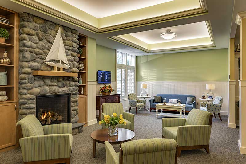 A modern living room with comfortable seating, a stone fireplace, and decorative elements including a boat model.