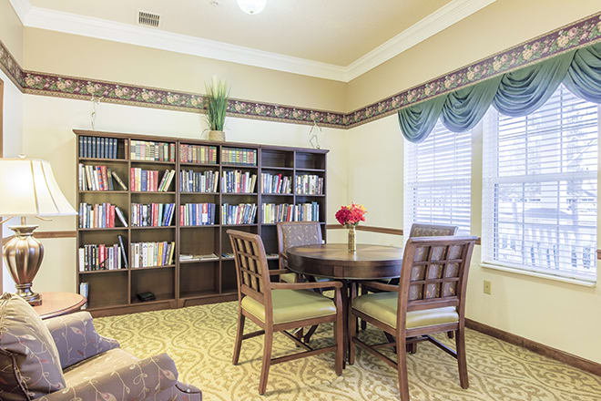 A cozy reading area with a round table and bookshelves in a well-lit room.