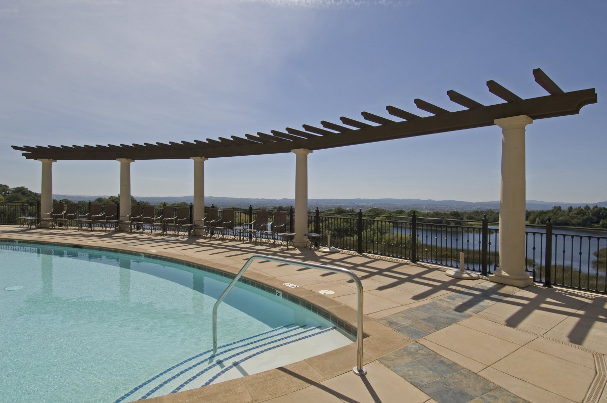 A scenic outdoor pool area with a pergola and panoramic views.