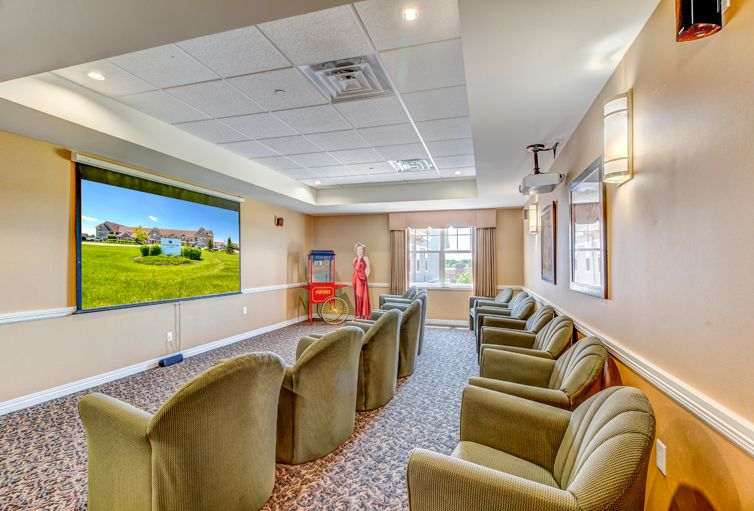 A cozy theater room with comfortable armchairs facing a large projector screen.