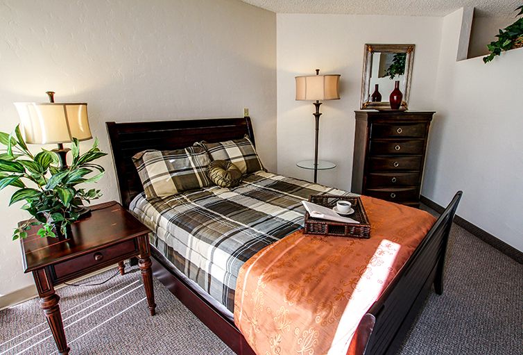 Cozy bedroom with a plaid bedspread and warm lighting.
