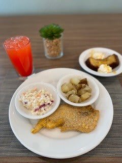 A meal consisting of fried chicken, potato salad, roasted potatoes, dessert, and a red drink.