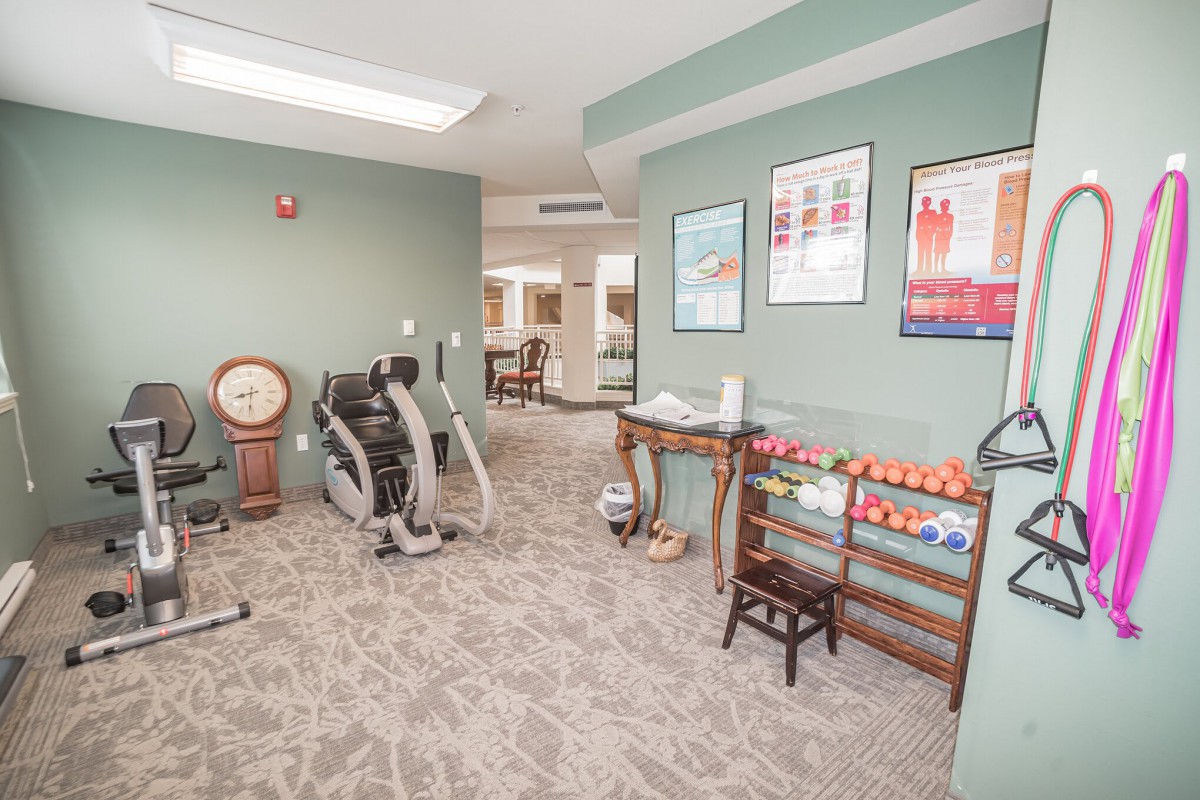 A small exercise room featuring stationary bikes, dumbbells, and motivational posters on the walls.