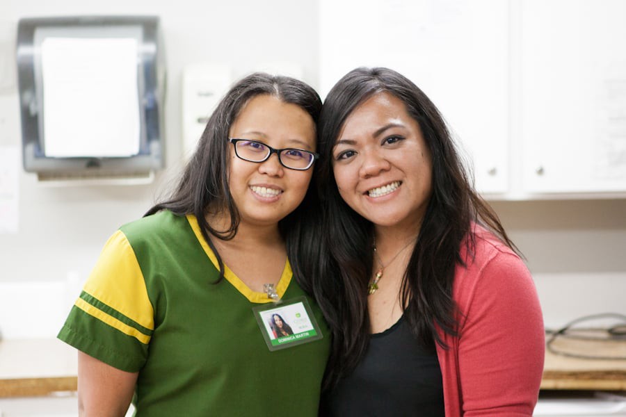 Two women smiling and posing together indoors.