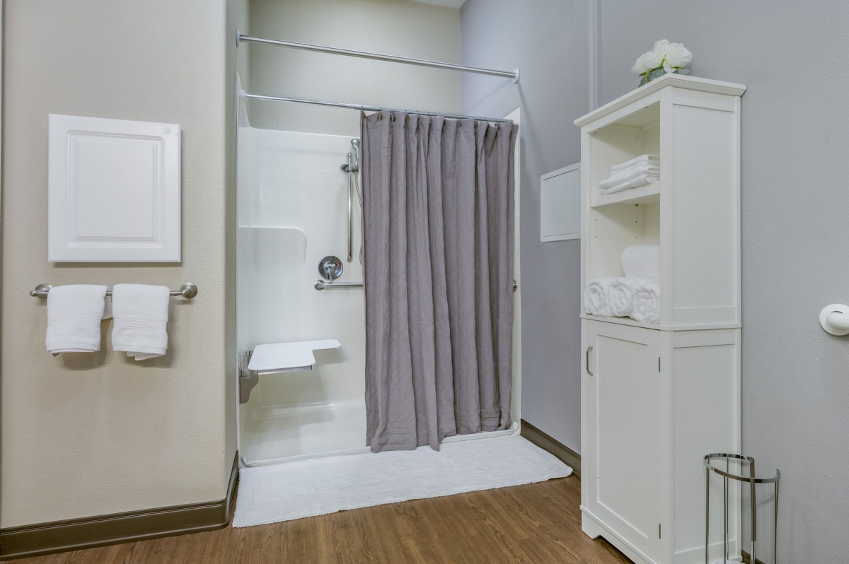 A clean and organized bathroom featuring a shower with a gray curtain and a white storage cabinet.