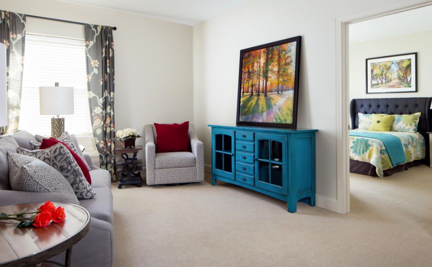 A modern living room featuring a blue cabinet and colorful artwork.