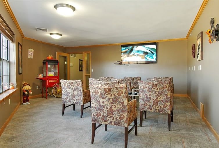 A cozy lounge area with patterned chairs, a television, and a popcorn machine.