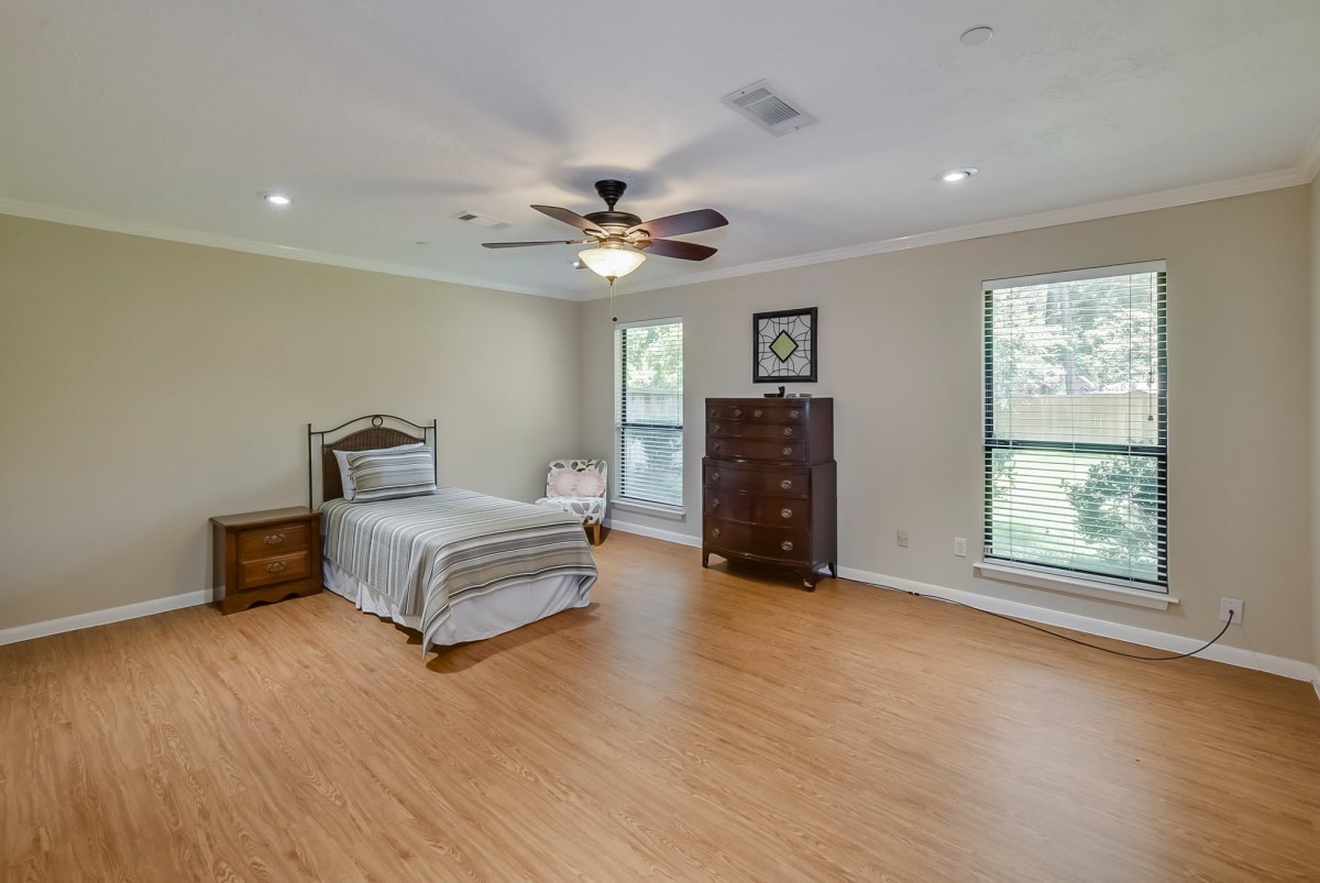 Spacious minimalist bedroom with a single bed and wooden flooring.