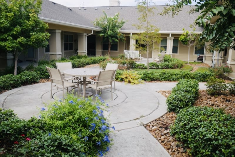 A serene garden patio with outdoor seating surrounded by well-maintained landscaping.