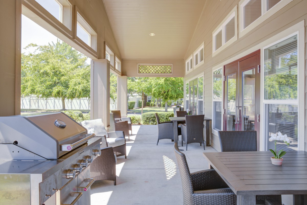 A spacious covered patio with outdoor seating and a grill, perfect for summer gatherings.