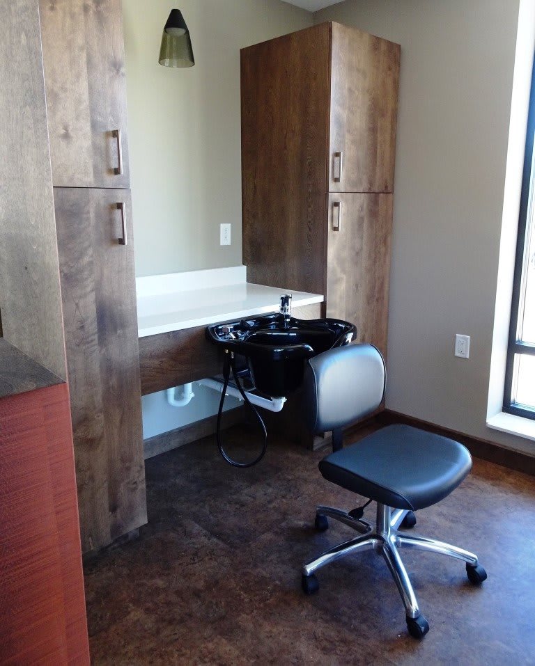 A salon hair washing station with a chair and mirror.