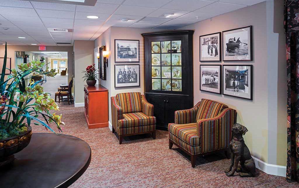 A cozy waiting area featuring two striped armchairs, framed artwork on the walls, and decorative elements.